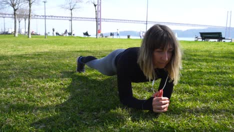 Concentrated-sporty-girl-doing-plank-exercise-on-grass